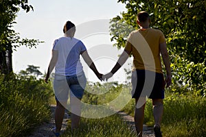 Couple holding hands while walking on a dirt road at sunset