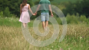 Couple holding hands and walking through the field