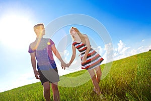 Couple holding hands and walking in green field