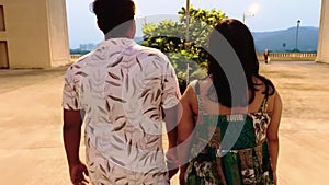 Couple holding hands walking together at dusk with urban background