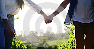 Couple holding hands while walking at a vineyard
