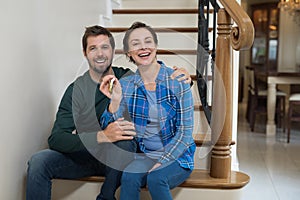 Couple holding house key while sitting on stairs