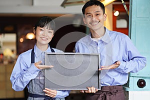 A couple holding a message board in front of a kitchen car