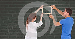 Couple holding picture frame against wall