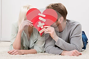 Couple Holding Red Paper Heart Fixed With Plaster Bandage