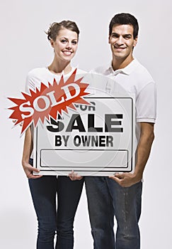 Couple Holding For Sale By Owners Sign