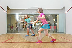 Couple holding squash racquets playing game match at fitness studio