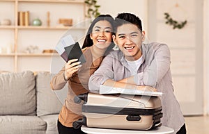 Couple Holding Tickets Sitting With Suitcase On Couch At Home