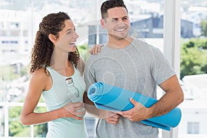 Couple holding water bottle and exercise mat