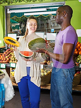 Couple is holding watermelon and melon in time shopping