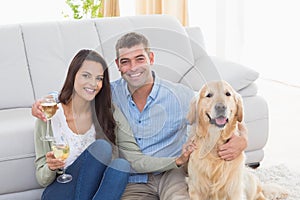 Couple holding wine glasses while sitting with dog