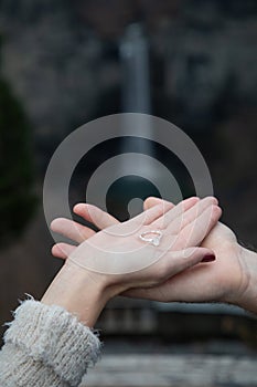 Couple holds engagement ring with waterfall