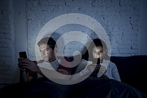 Couple at home in bed late at night using mobile phone in relationship communication problem