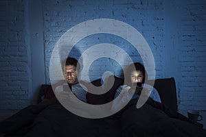 Couple at home in bed late at night using mobile phone in relationship communication problem photo