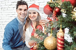 Couple at home decorating tree for Christmas