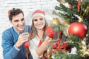 Couple at home decorating tree for Christmas