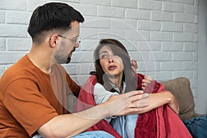 Couple at home. Handsome young man is calming his upset crying wife while holding her shoulders and apologizes. People,