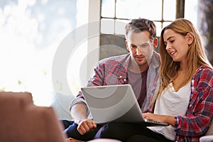 Couple At Home In Lounge Using Laptop Computer