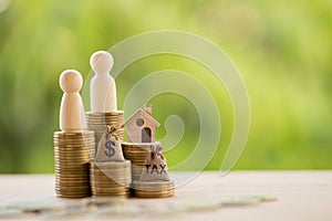 Couple and home model on rows of rising coins, US dollar bags on a table. Concept house or building or land value, property tax,