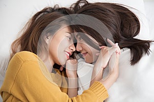 Couple of homosexual women on white bed,Lesbians Asian women are smiling and catching on white bed