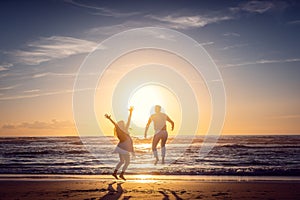 Couple on honeymoon during sunset on the beach jumping high
