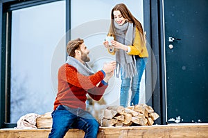 Couple with hot drinks near the house in the mountains