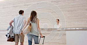 Couple, hotel and luggage walking to reception of a happy man and woman in luxury vacation or honeymoon. Young people in