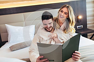 Couple in hotel room reading room service menu together
