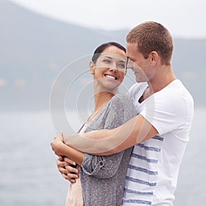 Couple, hug on beach and smile for travel, fresh air with ocean and happiness together outdoor. Romantic adventure, love