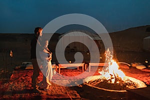 Couple hug in love near big campfire. Romantic night in glamping desert camp