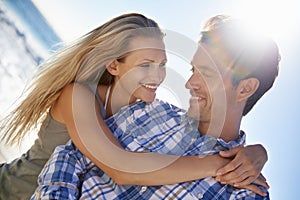 Couple, hug and smile outdoor at beach in summer sunshine for vacation, thinking and memory on travel. Man, woman and