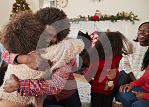 Couple Hugging As They Exchange Gifts At Multi Generation Family Christmas At Home