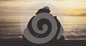 Couple hugging on background beach ocean sunrise, silhouette two romantic people cuddling and looking on rear view evening sea