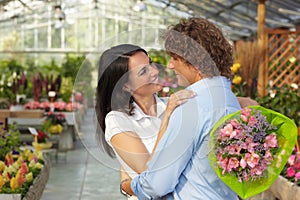 Couple hugging in flower nursery