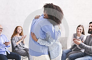 Couple Hugging In Front Of Group After Successful Marriage Therapy Session