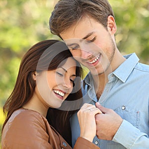 Couple hugging and holding hands while looks an engagement ring