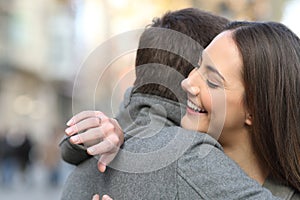 Couple hugging after proposal and girlfriend looking at ring