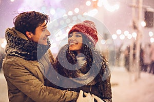 Couple Hugging Standing On A Street Decorated With Winter Lights