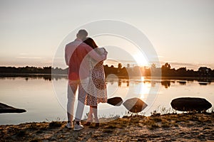 Couple hugging at sunset. Beautiful young couple in love walking along the lake at sunset in the rays of bright light. selective