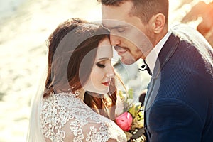 Couple hugging at sunset, lovers couple kissing in sunset. Wedding ceremony outdoors. Beautiful bride and groom with bouquet of f