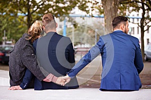 Couple hugging while the woman holding hands with another man