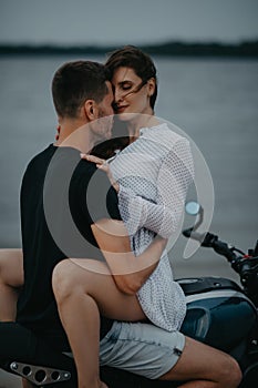 Couple hugs on beach sitting on motorcycle