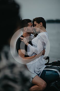 Couple hugs on beach sitting on motorcycle
