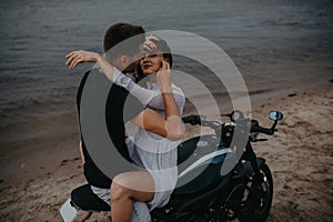 Couple hugs on beach sitting on motorcycle
