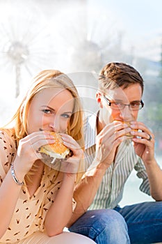 Couple is hungry and eating a burger at break