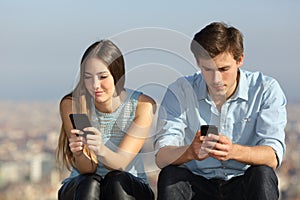 Couple ignoring each other addicted to smart phones