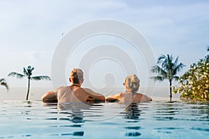 Couple in infinity pool looking at horizon