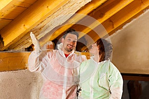 Couple installing thermal insulation to roof