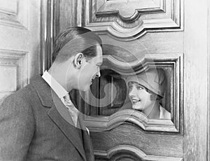 Couple interacting through hole in door