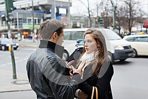 Couple In Jackets Communicating On Street Side